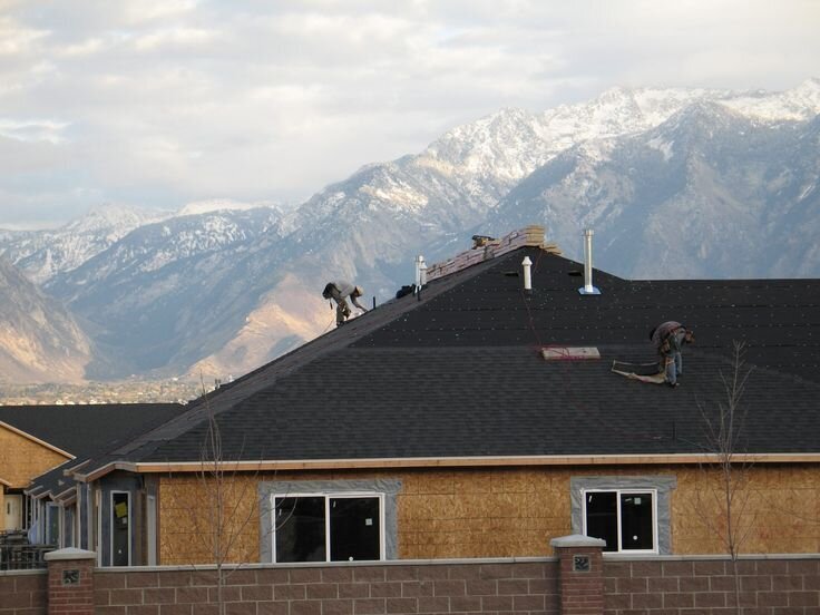 Sunset Restoration crew working on a residential roof with Colorado mountains in the background